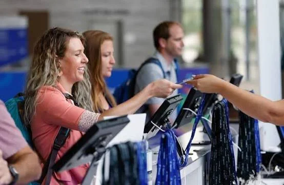 Guest List & Badge Management 1 Smiling registration host welcoming a guest at an event check-in desk with tablets