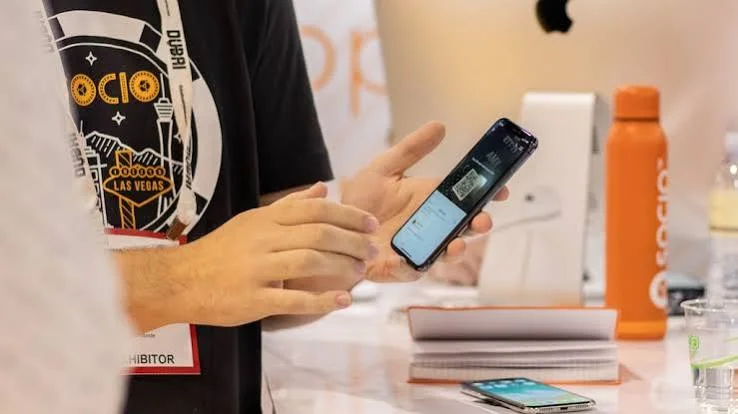 Exhibitor Lead Retrieval UAE 3 Hand holding a phone with a QR code up to a tablet scanner on a stand